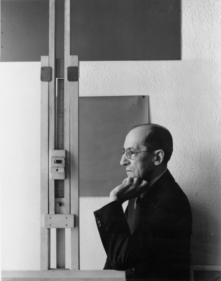 Piet Mondrian, leaning on an easel in his studio in New York