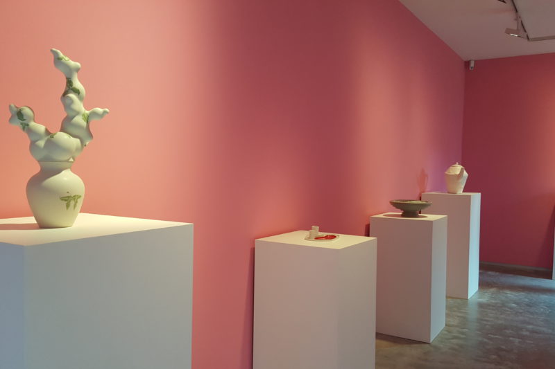 Overzicht van de tentoonstelling Dutch Design: Cor Unum in paviljoen Villa Mondriaan. Aardewerken objecten staan naast elkaar opgesteld op witte sokkels.