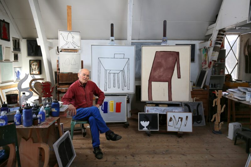 foto in kleur van Klaas Gubbels in zijn atelier met enkele van zijn werken
